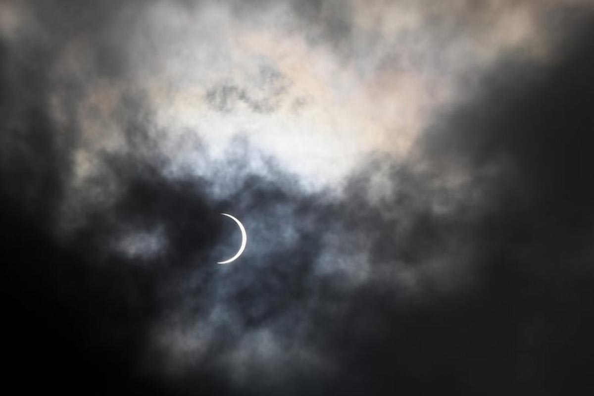La lune couvre partiellement le soleil pendant l'éclipse solaire annulaire, vue à travers les nuages depuis Karachi.