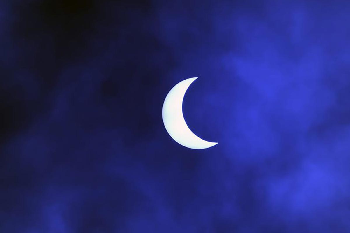 La lune se déplace devant le soleil pendant l'éclipse solaire annulaire, vue à travers les nuages depuis Katmandou.