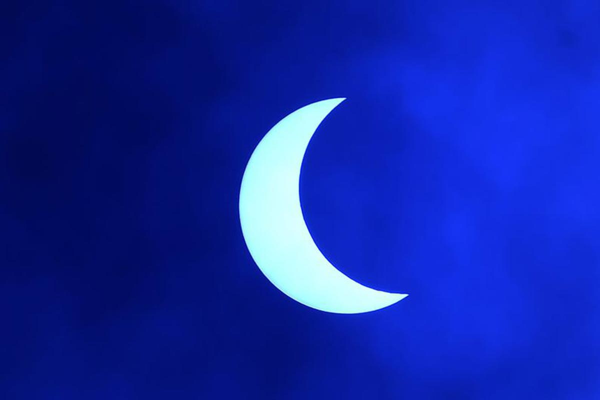 La lune se déplace devant le soleil pendant l'éclipse solaire annulaire, vue à travers les nuages depuis Katmandou.