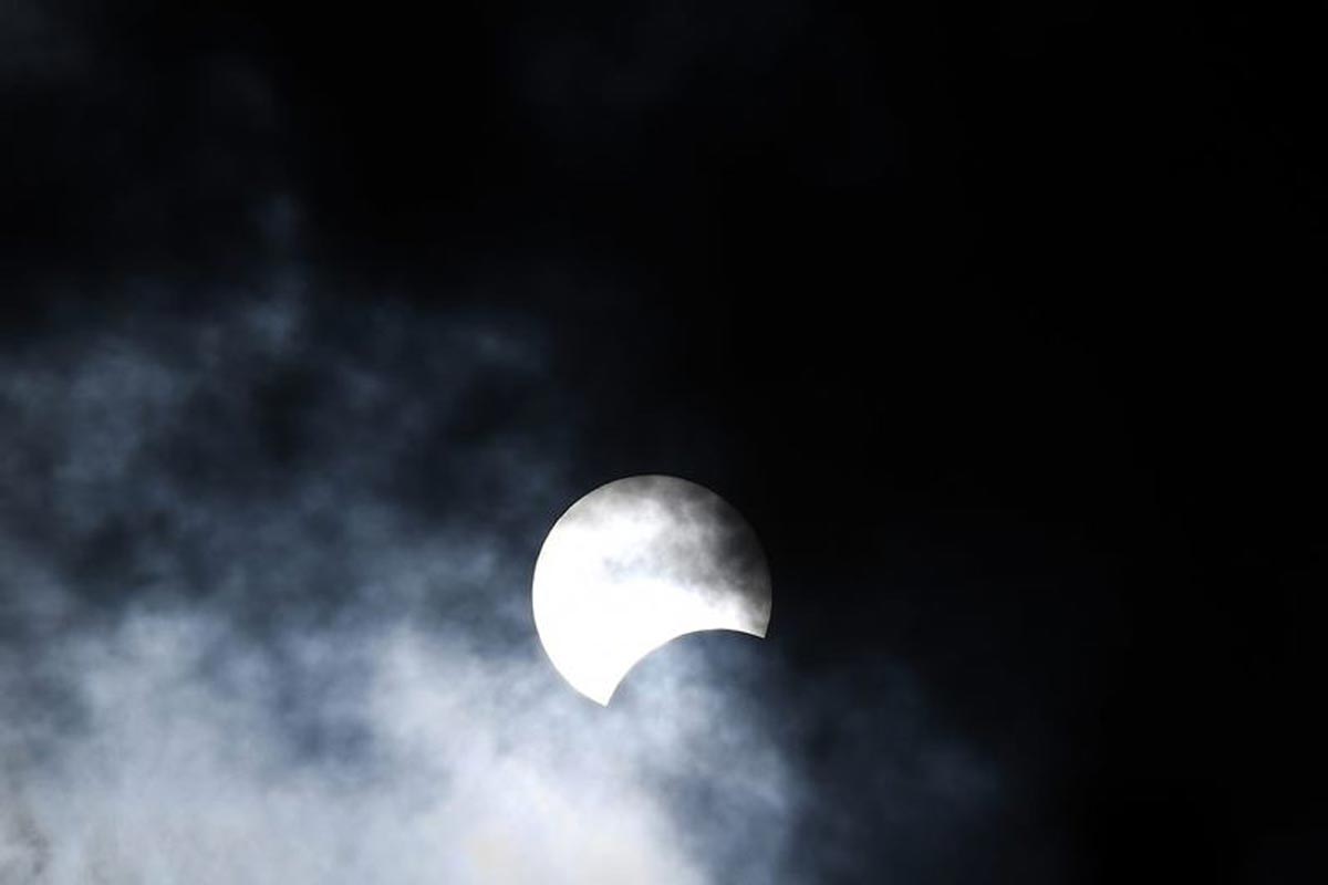 La lune se déplace devant le soleil pendant L'éclipse solaire annulaire vue à travers les nuages depuis Hanoi.