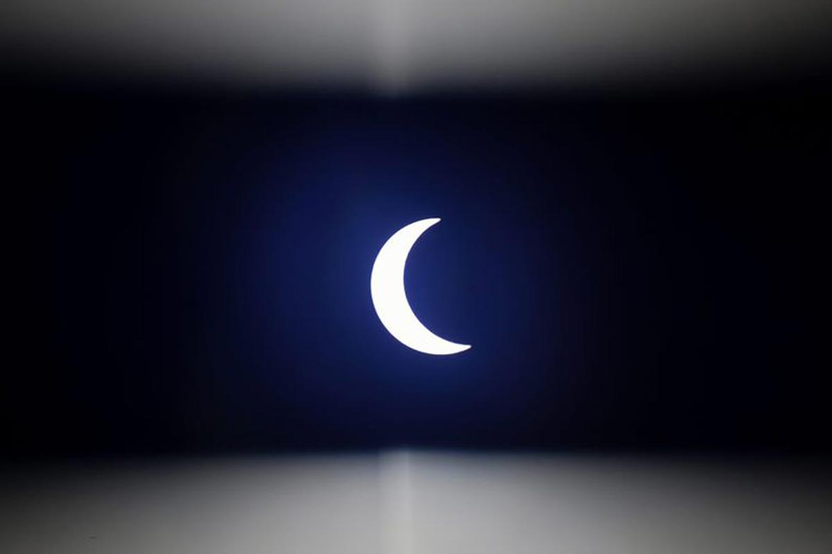 La lune se déplace devant le soleil, vue à travers une bande de plastique sombre, pendant l'éclipse solaire annulaire vue de l'extérieur de Hanoi.