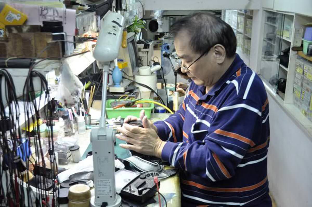 Un spécialiste, réparant un vieux Nikon dans son atelier.