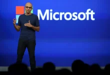 Satya Nadella sur scène lors d’une présentation Microsoft, devant un fond bleu avec le logo de l’entreprise
