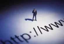 Un homme en costume debout sur une grande projection de texte représentant une URL, symbolisant l’importance des noms de domaine