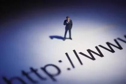 Un homme en costume debout sur une grande projection de texte représentant une URL, symbolisant l’importance des noms de domaine