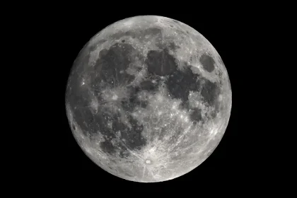 La Lune en pleine phase, vue avec un télescope astronomique, révélant les détails de sa surface avec des cratères et des nuances claires et sombres.