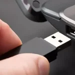 Une clé USB noire connectée à un port USB d'ordinateur portable, illustrant l'action de brancher un périphérique de stockage.