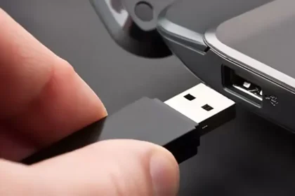 Une clé USB noire connectée à un port USB d'ordinateur portable, illustrant l'action de brancher un périphérique de stockage.