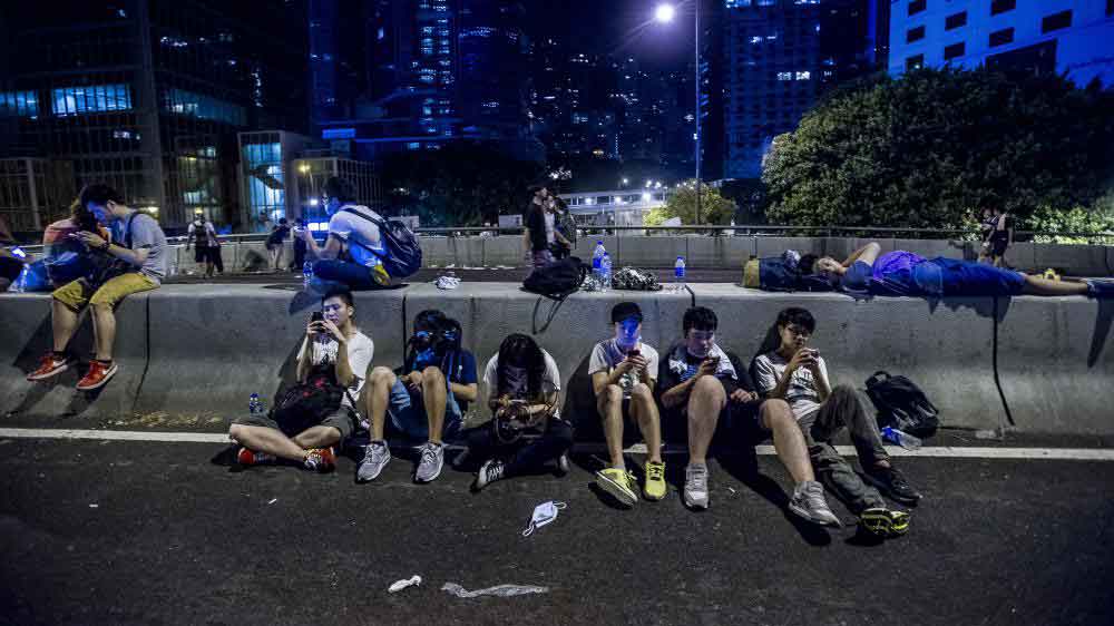 Des manifestants pro-démocratie consultent leur téléphone, à Hong Kong, le 29 septembre 2014.