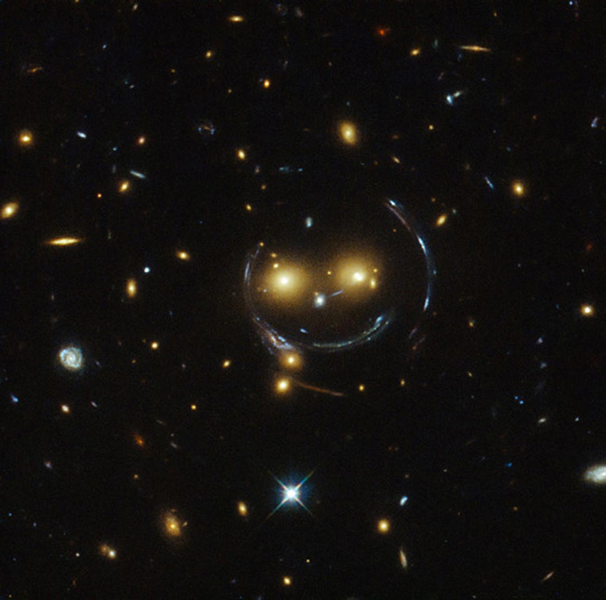 1. L'amas de galaxies SDSS J1038+4849 semble très souriant. Tout y est, ses deux yeux orange, son nez, le contour et la bouche. Ce phénomène est appelé « lentille gravitationnelle ». (Photo : NASA/ESA/Hubble)