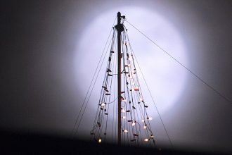 The Full Cold Moon rises behind Christmas tree lights on top of