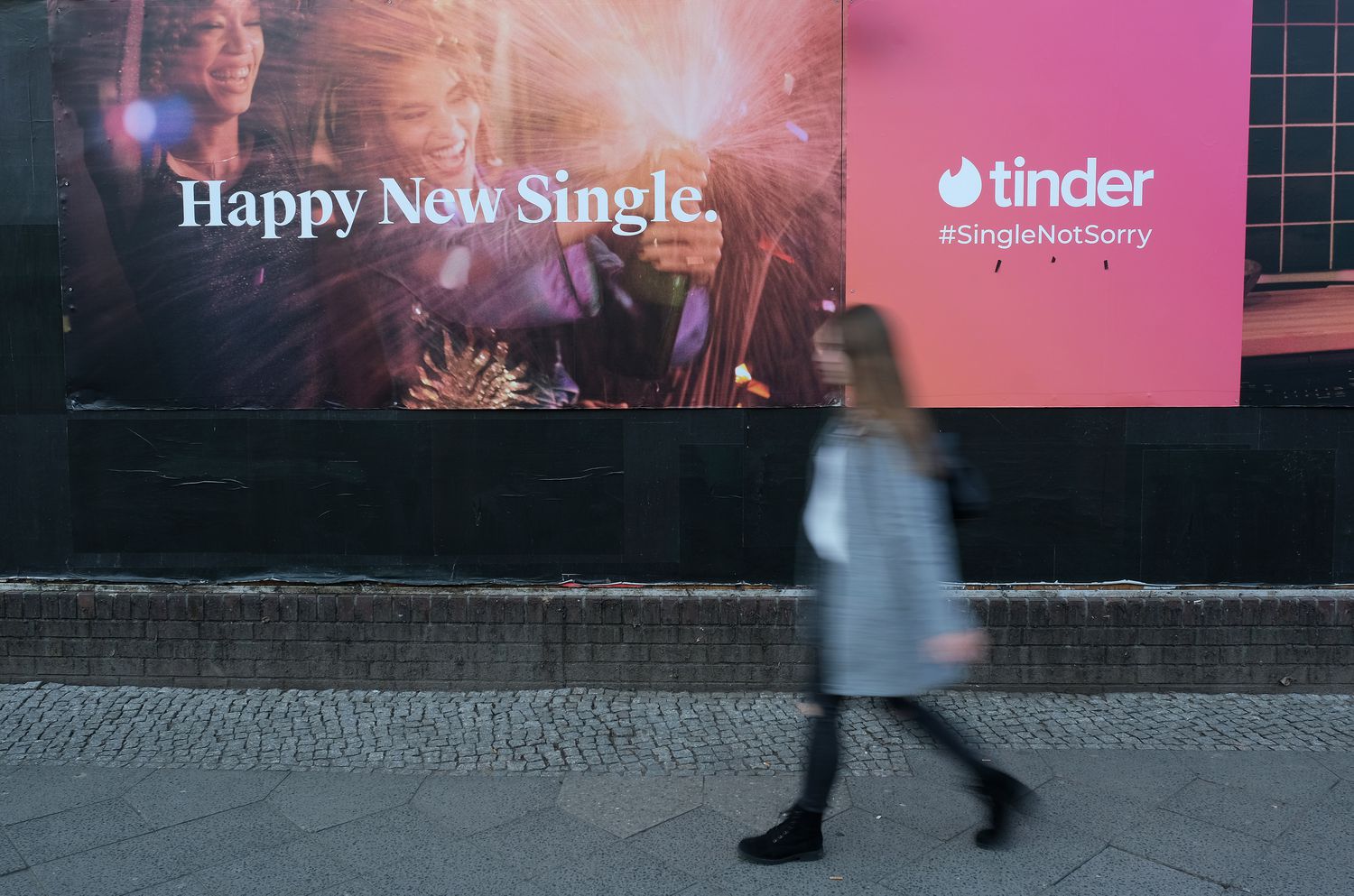 Une femme passe devant une annonce pour l'application de rencontres Tinder.