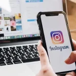 Suppression d’un compte Instagram depuis un smartphone, avec l’application affichée à l’écran devant un ordinateur portable