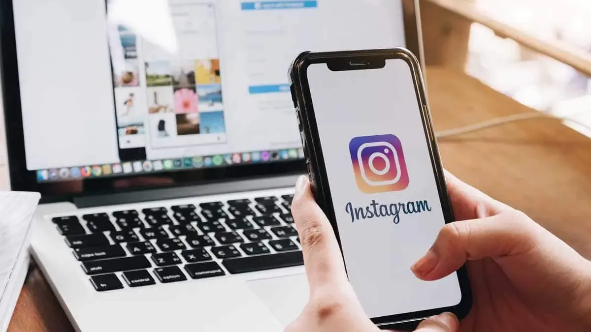 Suppression d’un compte Instagram depuis un smartphone, avec l’application affichée à l’écran devant un ordinateur portable