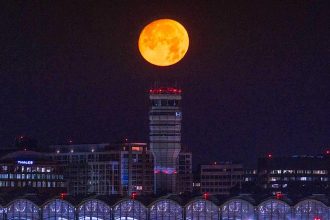 La lune presque pleine se couche sur l'aéroport national Reagan au début du 12 juillet 2022.