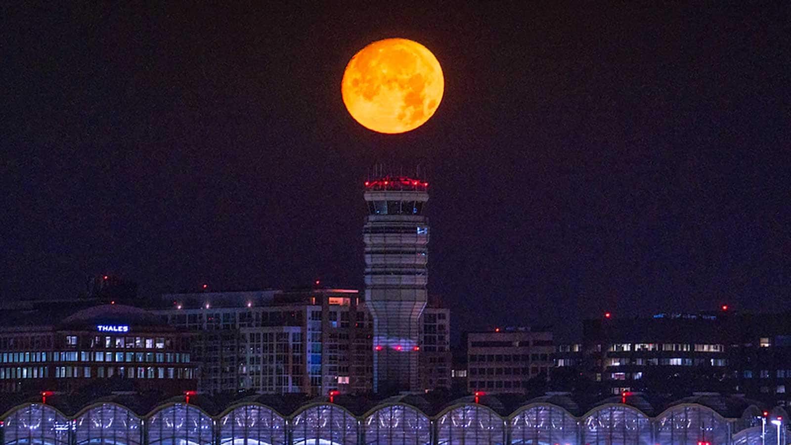 La lune presque pleine se couche sur l'aéroport national Reagan au début du 12 juillet 2022.