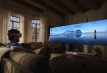 Un homme portant un casque Apple Vision Pro assis sur un canapé, regardant une projection immersive d'un paysage de montagne glacée.