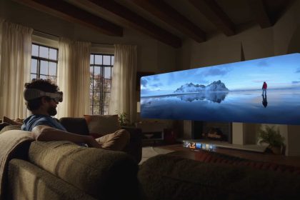 Un homme portant un casque Apple Vision Pro assis sur un canapé, regardant une projection immersive d'un paysage de montagne glacée.