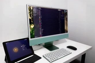 Écran d'un iMac affichant l'application CyberGhost VPN, avec un iPad Pro connecté au VPN, sur un bureau minimaliste.