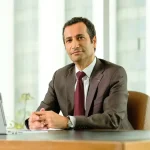 Mohamed Benchaâboun en costume professionnel assis à son bureau, illustrant la gouvernance de Maroc Telecom