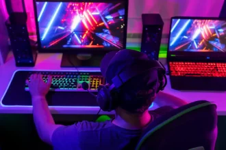 Joueur sur PC équipé d’un casque, en pleine session gaming avec affichage coloré sur deux écrans.