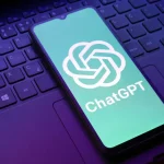 Smartphone affichant le logo ChatGPT posé sur le clavier d’un ordinateur portable, illustrant l’intégration de l’IA dans les usages numériques quotidiens.