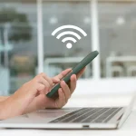 Personne utilisant un smartphone pour partager une connexion WiFi avec un ordinateur portable.