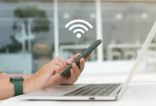 Personne utilisant un smartphone pour partager une connexion WiFi avec un ordinateur portable.