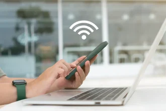 Personne utilisant un smartphone pour partager une connexion WiFi avec un ordinateur portable.