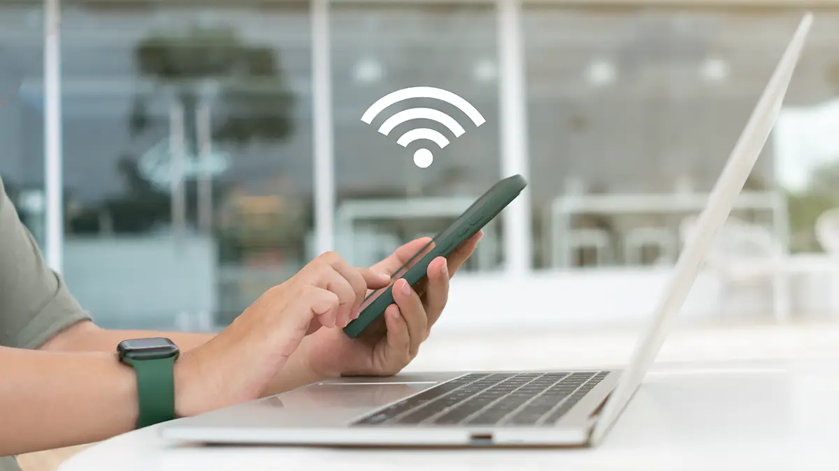 Personne utilisant un smartphone pour partager une connexion WiFi avec un ordinateur portable.