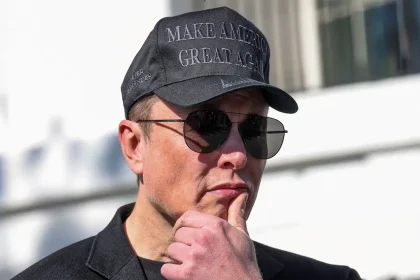 Elon Musk portant une casquette noire et des lunettes de soleil, pensif