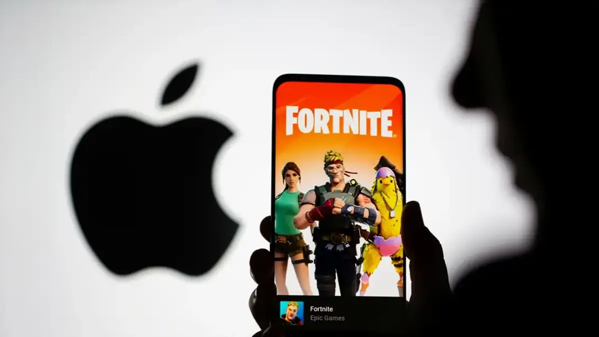 Un smartphone affichant l’écran d’accueil de Fortnite devant le logo Apple en arrière-plan.