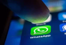 Icône WhatsApp sur smartphone sous un doigt, interface mobile en gros plan