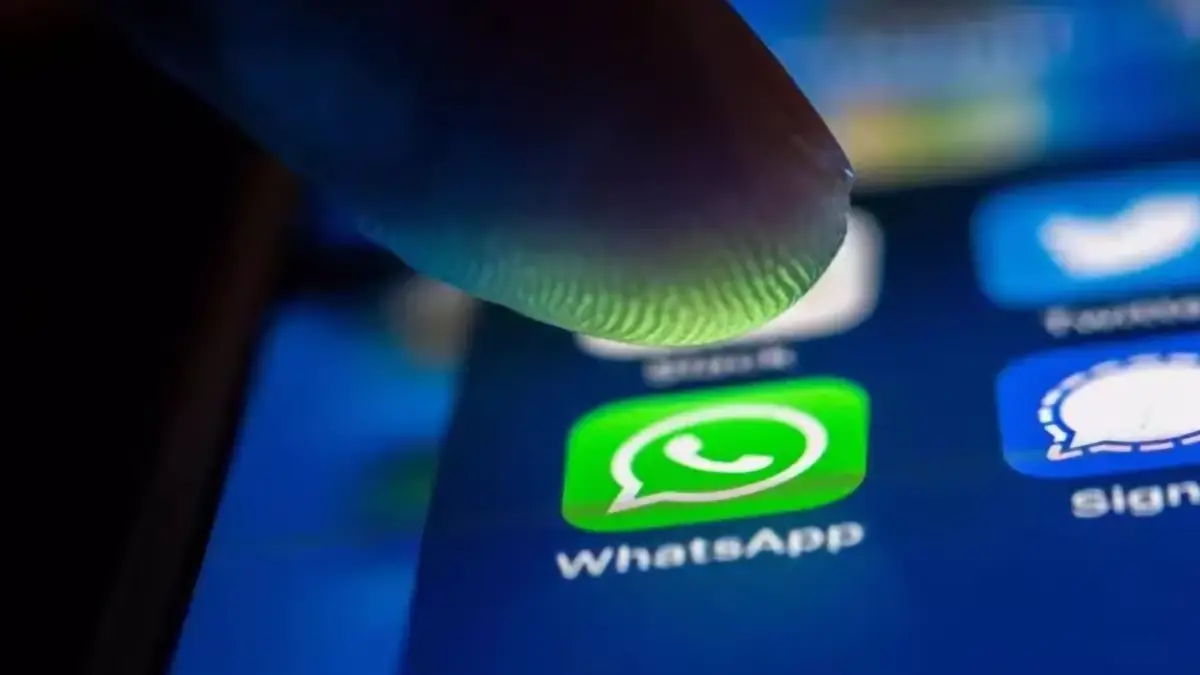 Icône WhatsApp sur smartphone sous un doigt, interface mobile en gros plan
