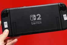 Console Nintendo Switch 2 noire vue de dos avec logo central visible, tenue en main