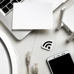 Vue de dessus d’un routeur Wi-Fi entouré d’appareils connectés, smartphone, câble réseau et robot aspirateur