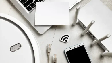 Vue de dessus d’un routeur Wi-Fi entouré d’appareils connectés, smartphone, câble réseau et robot aspirateur