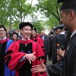 Mark Zuckerberg en toge universitaire échange avec un diplômé lors d'une cérémonie à Harvard