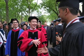 Mark Zuckerberg en toge universitaire échange avec un diplômé lors d'une cérémonie à Harvard