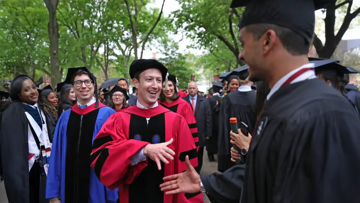 Mark Zuckerberg en toge universitaire échange avec un diplômé lors d'une cérémonie à Harvard