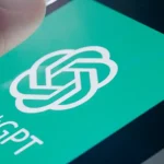 Main posée sur l’écran d’un smartphone affichant le logo vert de ChatGPT