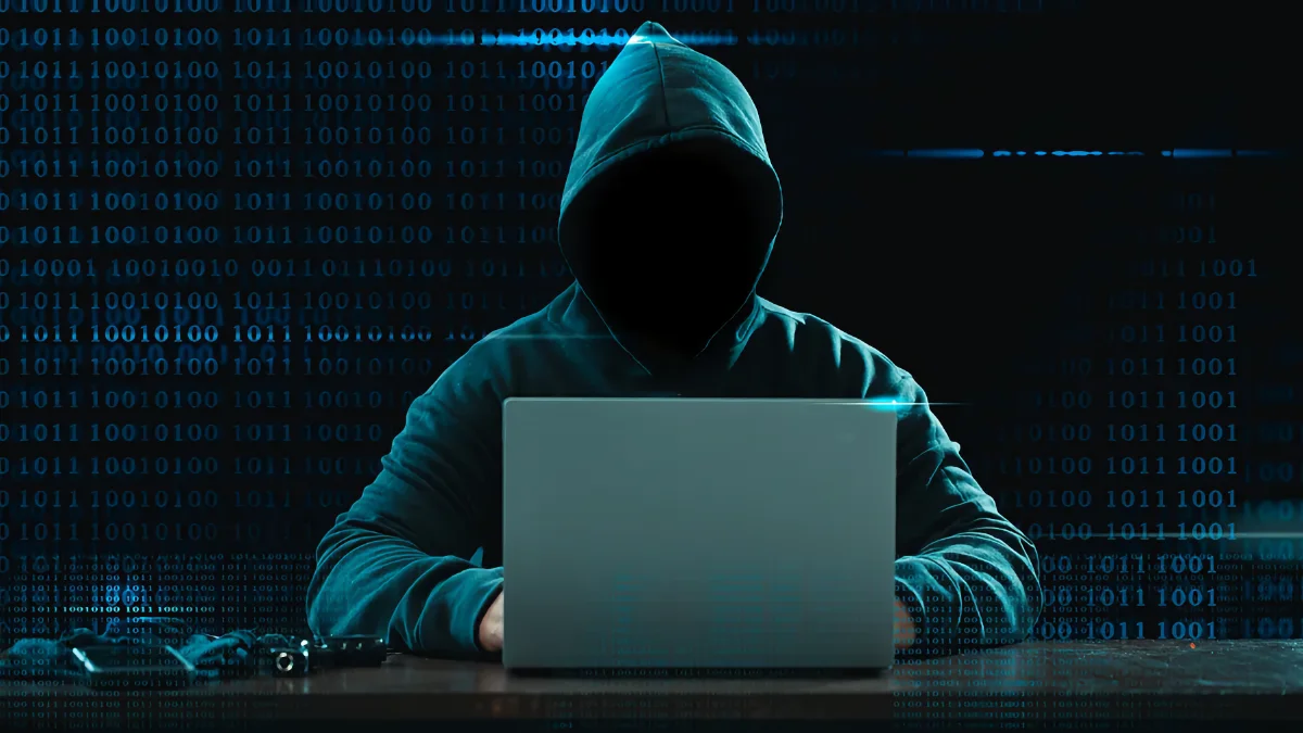 Faux antivirus Android, silhouette encapuchonnée devant un portable sur fond de code, illustration d’une menace d’app espion.