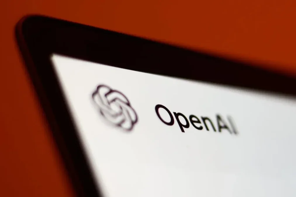 Logo d’OpenAI affiché sur l’écran d’une tablette, sur fond rouge