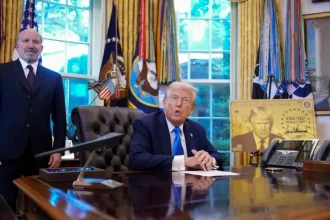 Le président signe une proclamation H-1B dans le Bureau ovale aux côtés d’un conseiller.