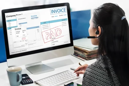 Femme travaillant sur un ordinateur affichant une facture payée, illustrant un logiciel de facturation pour TPE.