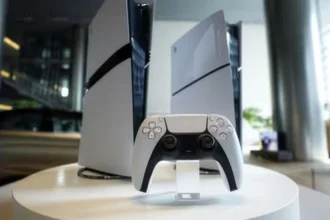 Deux consoles PlayStation 5 et une manette DualSense posées sur un socle blanc.