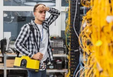 Technicien réseau fatigué observant un serveur après une panne AWS